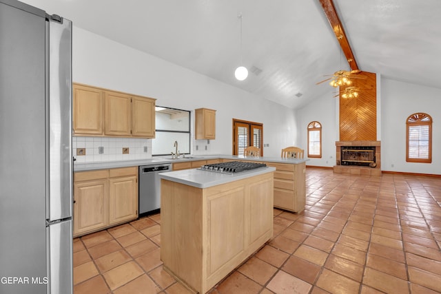 kitchen with a sink, beamed ceiling, light brown cabinetry, and stainless steel appliances