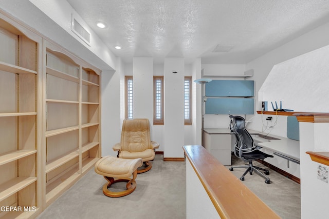 office area featuring visible vents, a textured ceiling, built in desk, carpet flooring, and baseboards