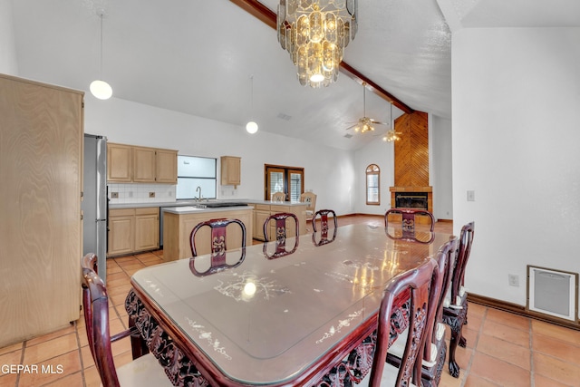 dining space with beamed ceiling, a large fireplace, a healthy amount of sunlight, and a ceiling fan