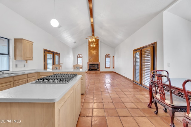 kitchen featuring a healthy amount of sunlight, light brown cabinets, stainless steel gas cooktop, beam ceiling, and light countertops