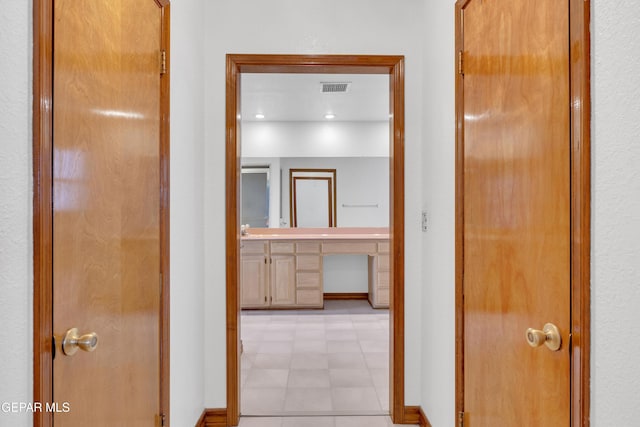 hall featuring visible vents, light floors, and baseboards