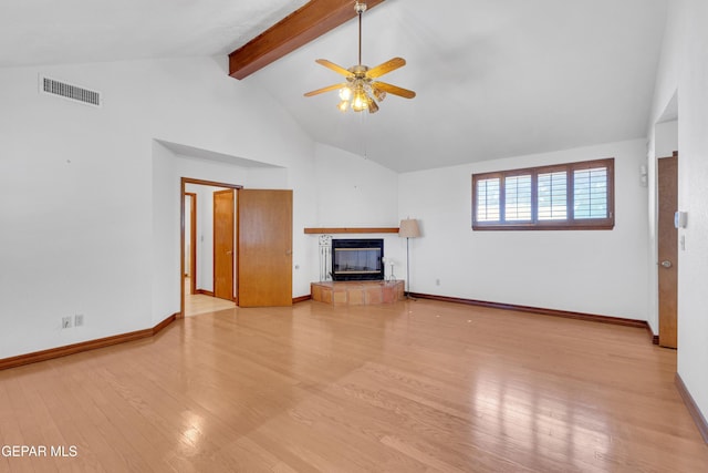 unfurnished living room featuring wood finished floors, visible vents, a ceiling fan, a tiled fireplace, and beamed ceiling