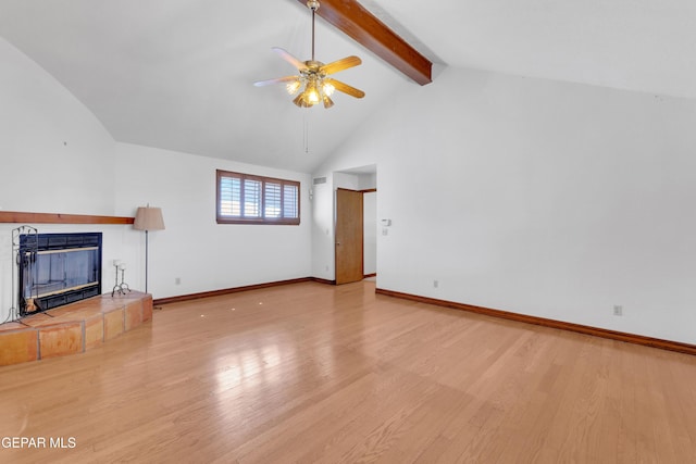 unfurnished living room with a tiled fireplace, beamed ceiling, baseboards, and wood finished floors