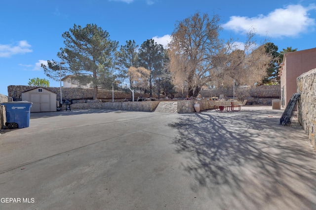 view of yard featuring a patio area, a storage shed, an outdoor structure, and fence