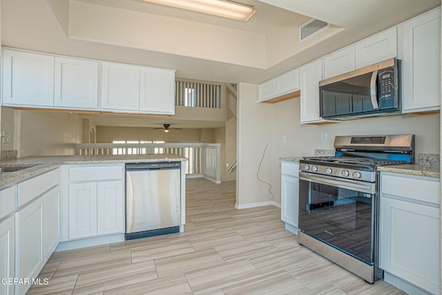 kitchen with white cabinetry, light stone counters, appliances with stainless steel finishes, and ceiling fan