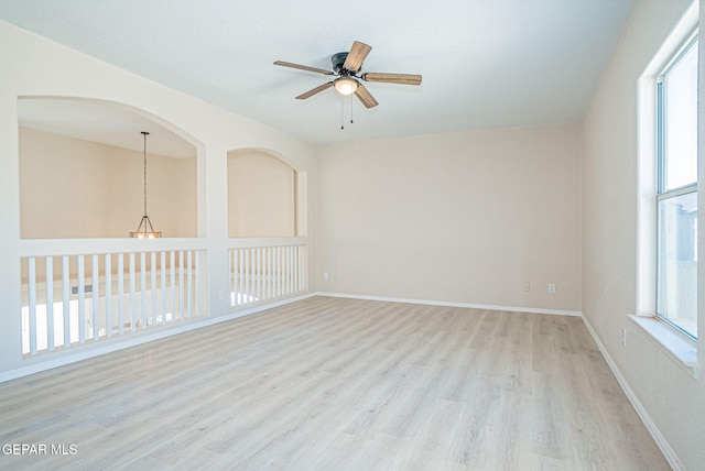 spare room with baseboards, light wood-style floors, and a ceiling fan