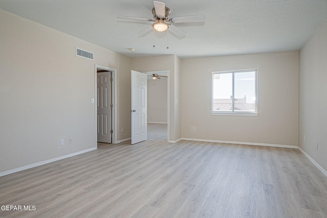 unfurnished bedroom featuring visible vents, a textured ceiling, light wood-type flooring, and baseboards