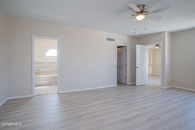 spare room with a textured ceiling, baseboards, visible vents, and light wood-type flooring