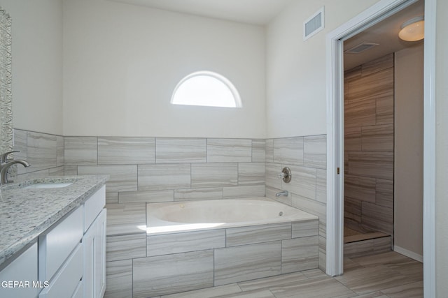 full bathroom with visible vents, a garden tub, and vanity