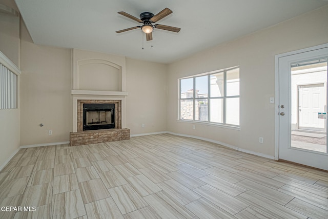 unfurnished living room with a fireplace, baseboards, ceiling fan, and wood tiled floor