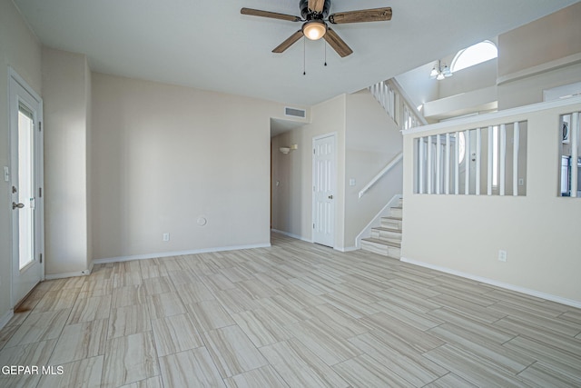 unfurnished room with light wood-type flooring, visible vents, a ceiling fan, stairway, and baseboards