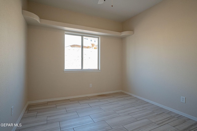 spare room with a ceiling fan and baseboards