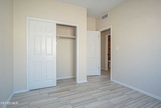 unfurnished bedroom with baseboards, visible vents, and a closet