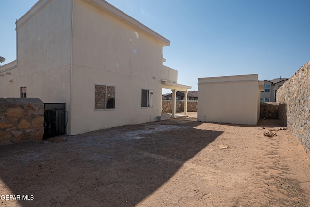 back of property with an outdoor structure, fence, and stucco siding