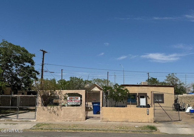 view of front facade featuring a fenced front yard, stucco siding, and a gate