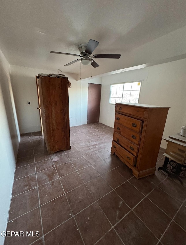 unfurnished bedroom featuring dark tile patterned floors and a ceiling fan