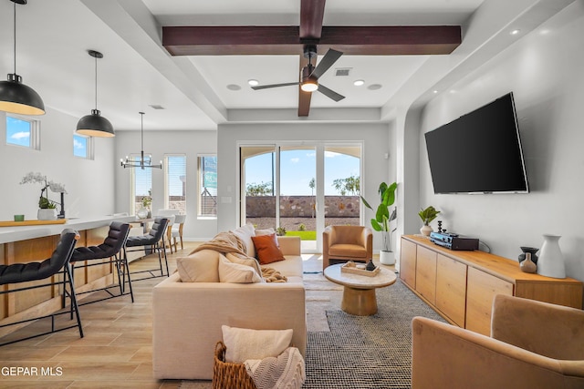 living area featuring beam ceiling, plenty of natural light, ceiling fan with notable chandelier, and wood finish floors