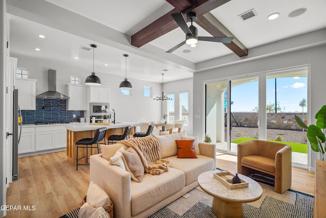 living area with visible vents, beam ceiling, ceiling fan with notable chandelier, recessed lighting, and light wood finished floors