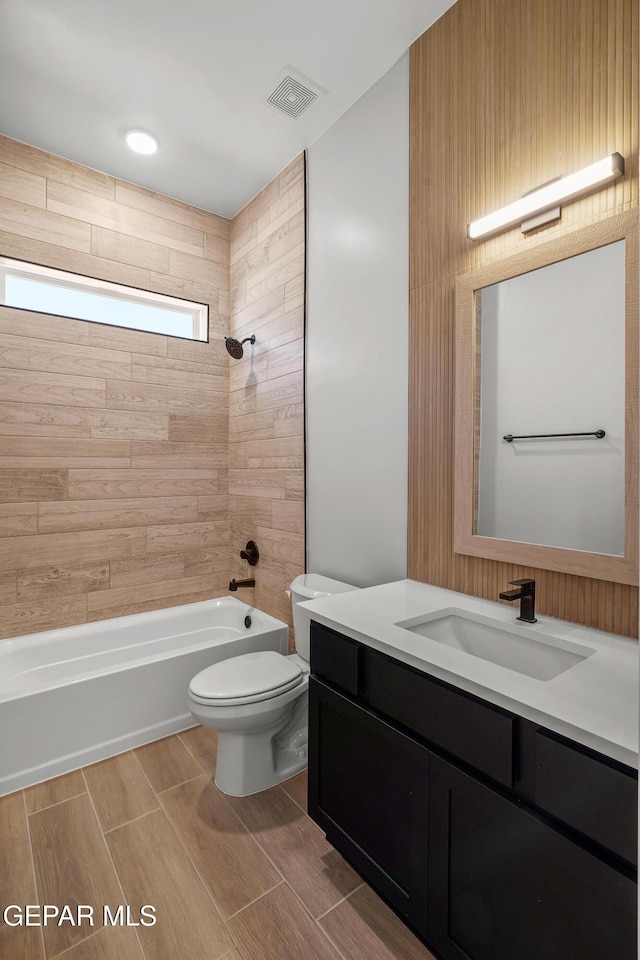 bathroom featuring wood finish floors, visible vents, toilet, shower / tub combination, and vanity