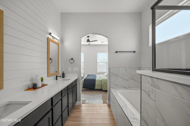 full bathroom with a sink, double vanity, wood tiled floor, and a washtub