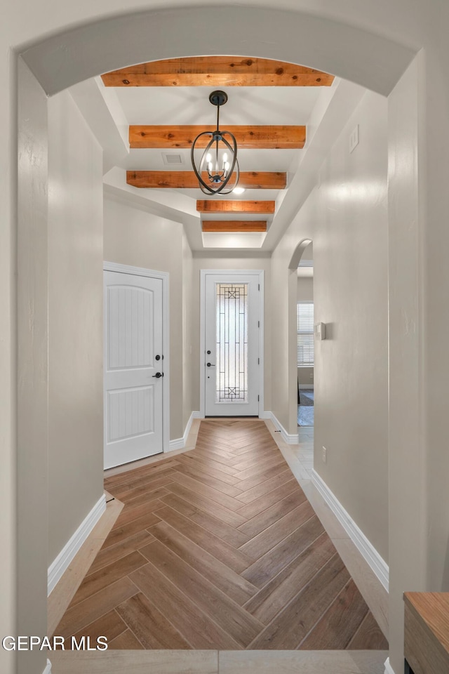 foyer with baseboards, beam ceiling, arched walkways, parquet floors, and a chandelier