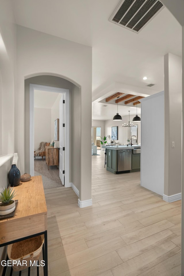 hall with beamed ceiling, visible vents, light wood-style flooring, and baseboards