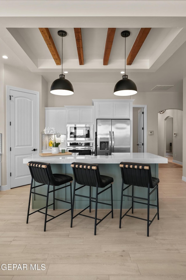 kitchen with a kitchen breakfast bar, tasteful backsplash, arched walkways, and appliances with stainless steel finishes