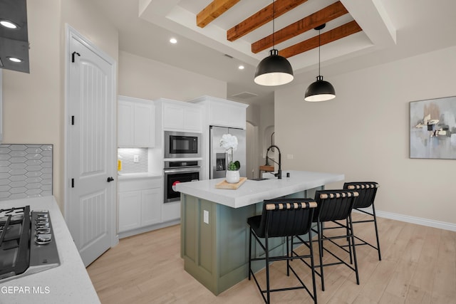 kitchen with decorative backsplash, light wood-style flooring, appliances with stainless steel finishes, and a sink