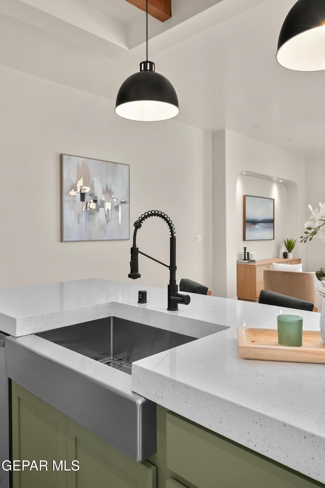 kitchen featuring a sink, pendant lighting, light stone counters, and green cabinetry