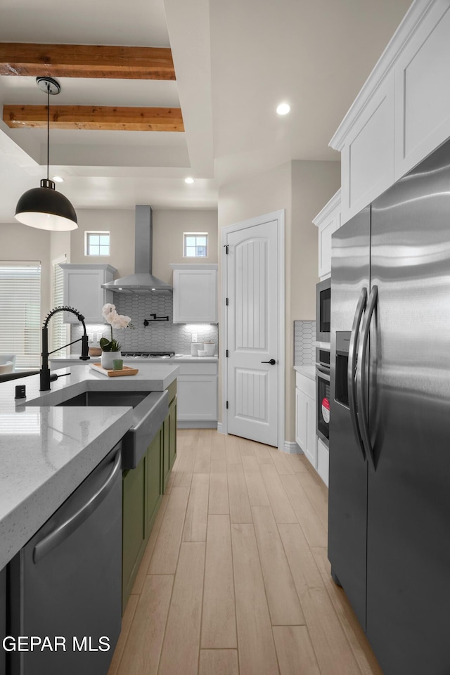 kitchen featuring tasteful backsplash, white cabinets, stainless steel appliances, and wall chimney exhaust hood