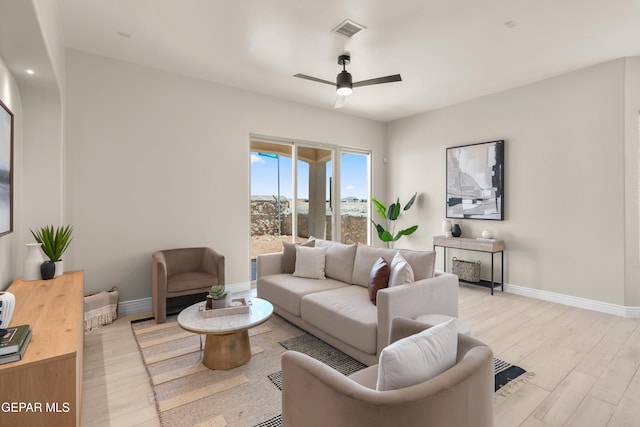 living room featuring visible vents, baseboards, light wood-style floors, and a ceiling fan