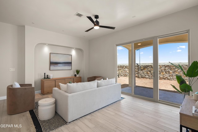 living room featuring light wood-style flooring, baseboards, visible vents, and ceiling fan