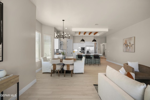 dining room with visible vents, baseboards, light wood-style flooring, arched walkways, and a notable chandelier