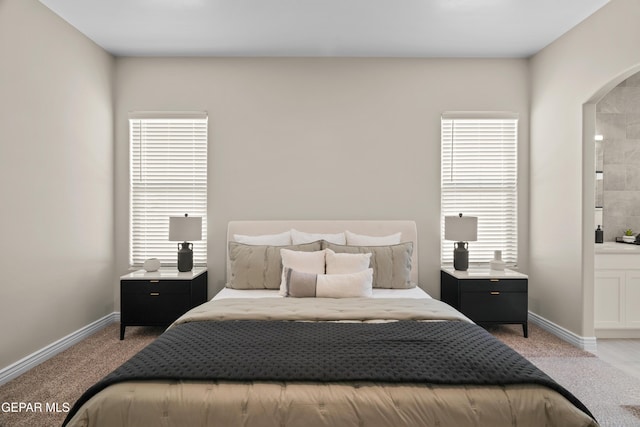 carpeted bedroom with arched walkways and baseboards