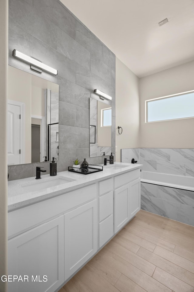 bathroom with double vanity, tile walls, and a sink