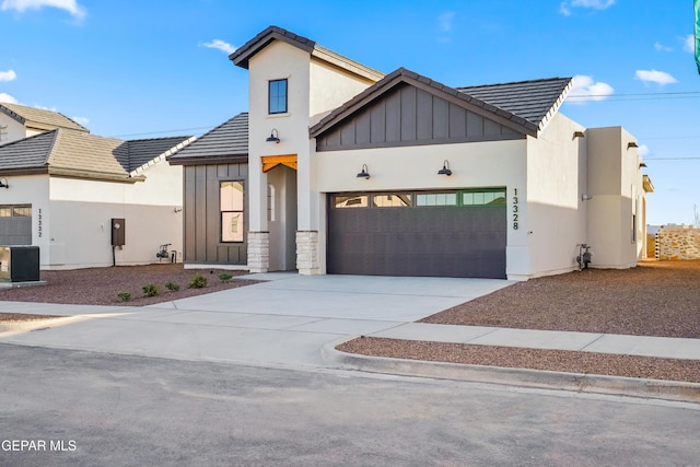 view of front of house with a tiled roof, an attached garage, driveway, and board and batten siding