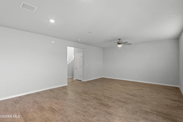 spare room with a ceiling fan, wood finished floors, visible vents, and baseboards