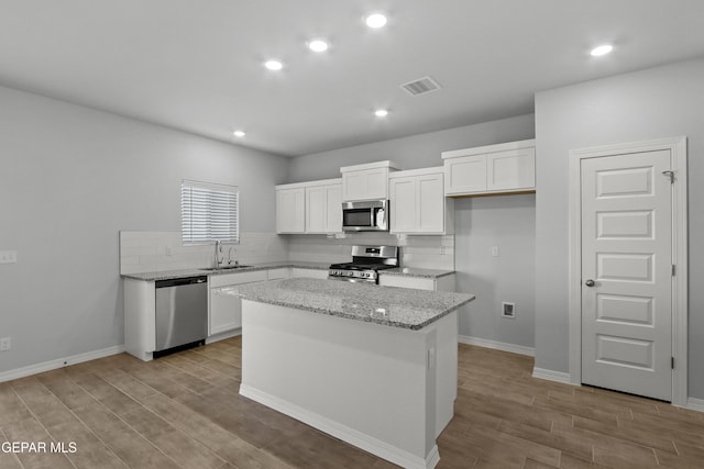 kitchen with light wood finished floors, stainless steel appliances, tasteful backsplash, and a sink