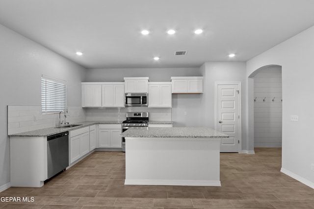 kitchen featuring visible vents, a sink, a kitchen island, white cabinetry, and appliances with stainless steel finishes