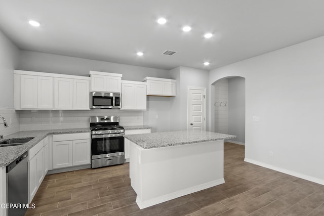 kitchen featuring visible vents, arched walkways, a sink, decorative backsplash, and stainless steel appliances