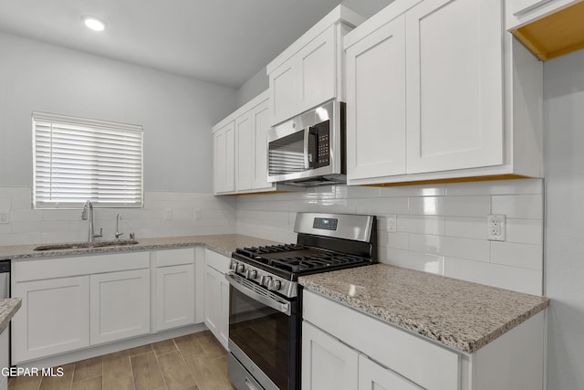 kitchen featuring a sink, light stone counters, white cabinetry, and stainless steel appliances