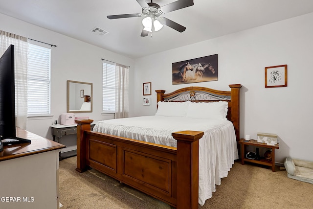 bedroom with ceiling fan, visible vents, and light carpet