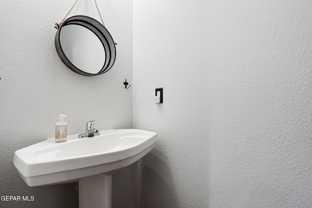 bathroom featuring a textured wall and a sink