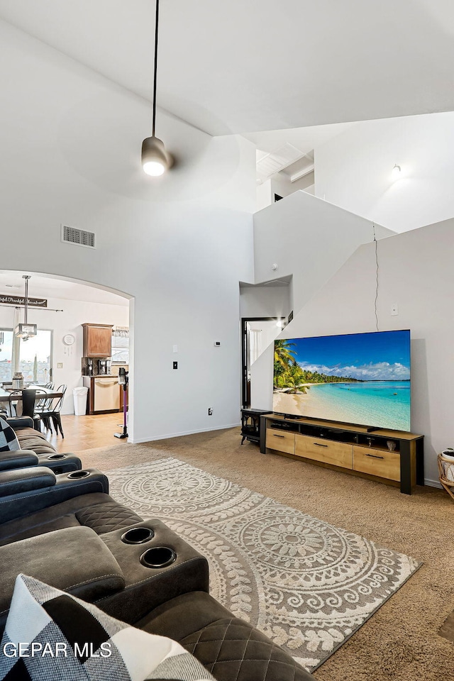 living room featuring visible vents, a towering ceiling, and carpet floors