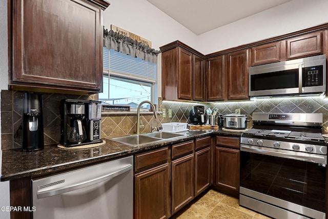 kitchen featuring dark stone counters, tasteful backsplash, appliances with stainless steel finishes, and a sink