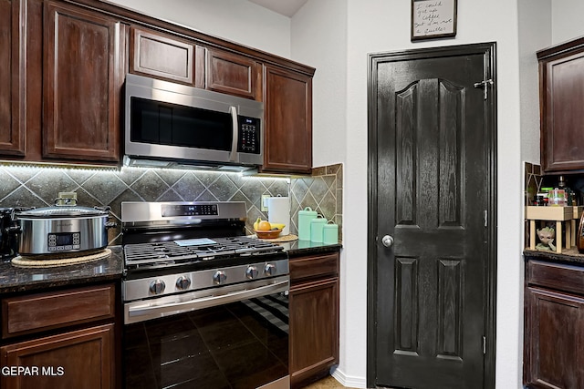 kitchen featuring decorative backsplash, dark brown cabinets, appliances with stainless steel finishes, and dark stone counters