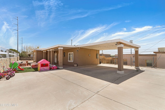 rear view of property with a carport, driveway, and fence