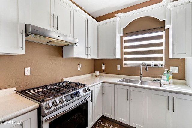 kitchen with under cabinet range hood, stainless steel gas stove, and white cabinetry