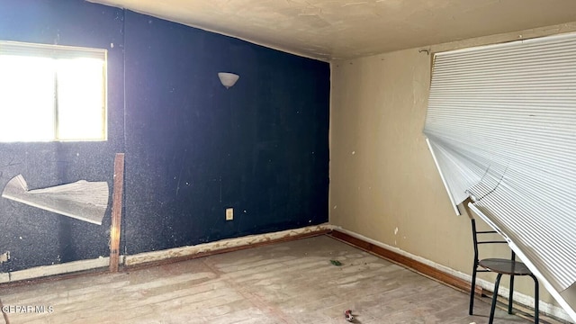 spare room featuring baseboards and wood finished floors