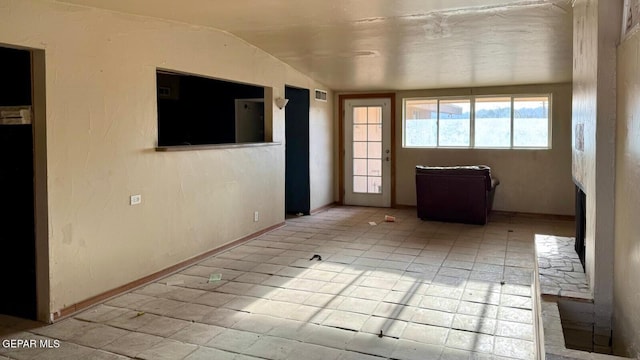 spare room featuring visible vents, baseboards, and vaulted ceiling